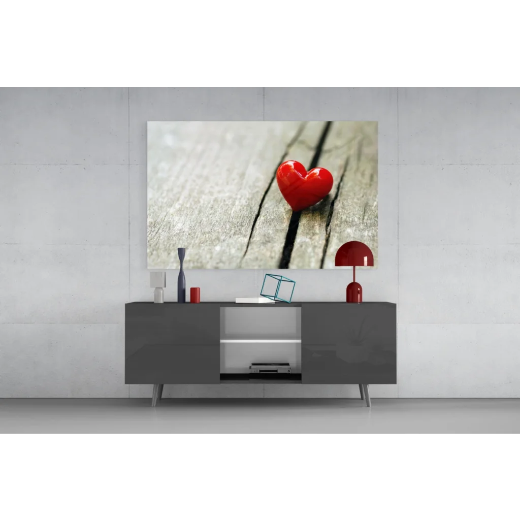 Vibrant red heart glass wall art on light wood surface