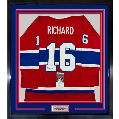 Framed red, white, and blue Montreal Canadiens jersey number 16 signed by Henri Richard, displayed front-facing in protective case.