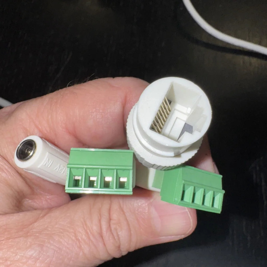 Hand holding white and green connectors for Hikvision dome network camera