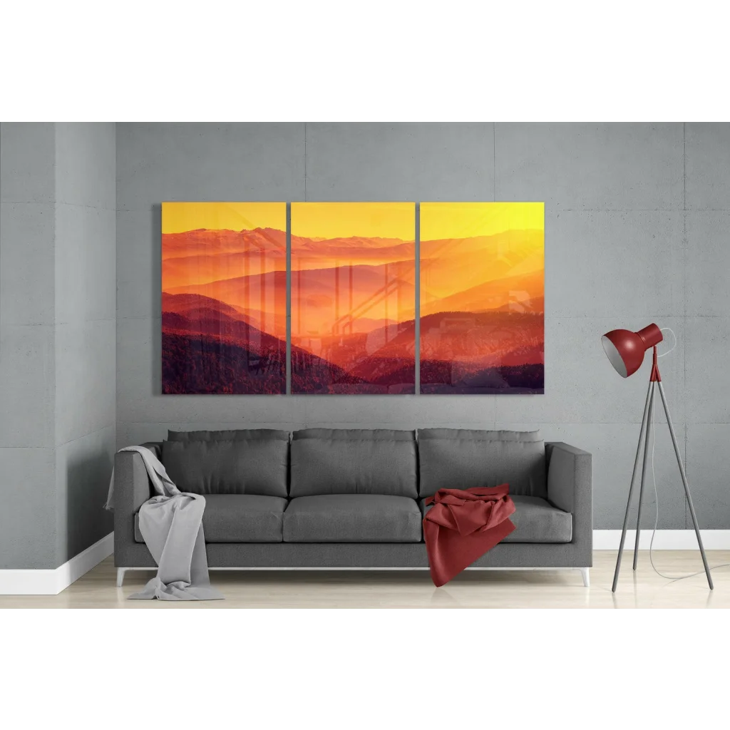 Vibrant orange yellow mountain sunrise glass wall art triptych above gray sofa
