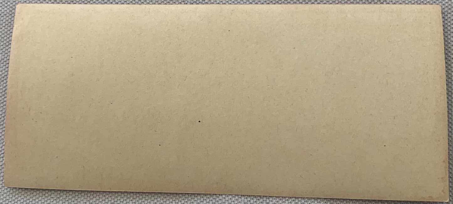Blank cream-colored vintage sausage label on gray textured fabric background, showing wear and age spots