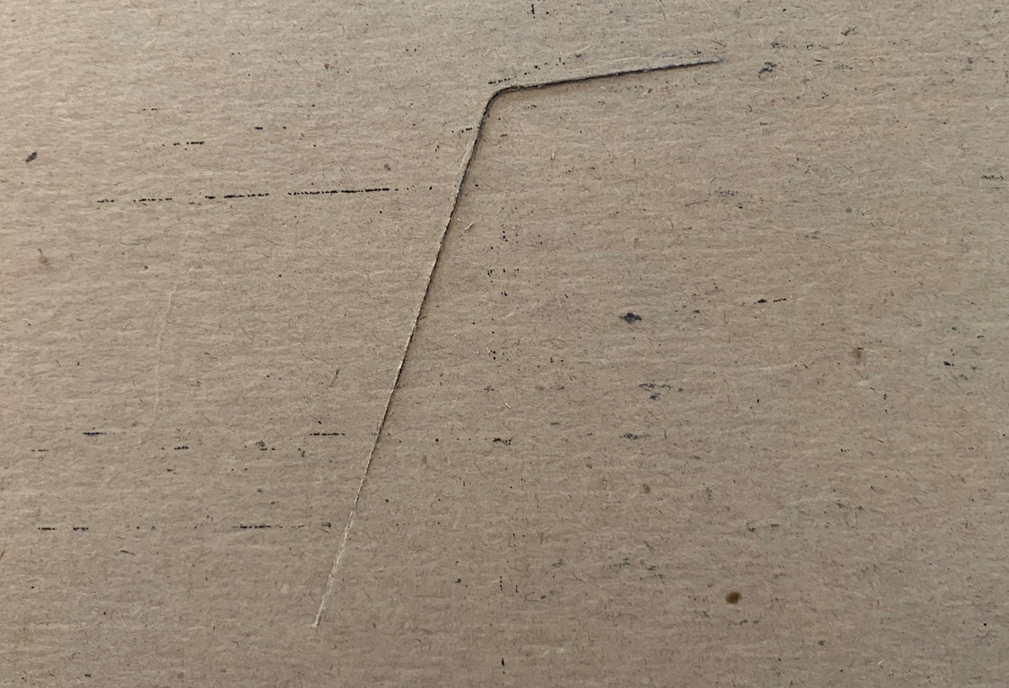 Close-up of a concrete or cement surface with a diagonal seam or joint line running across it, showing texture and small dark