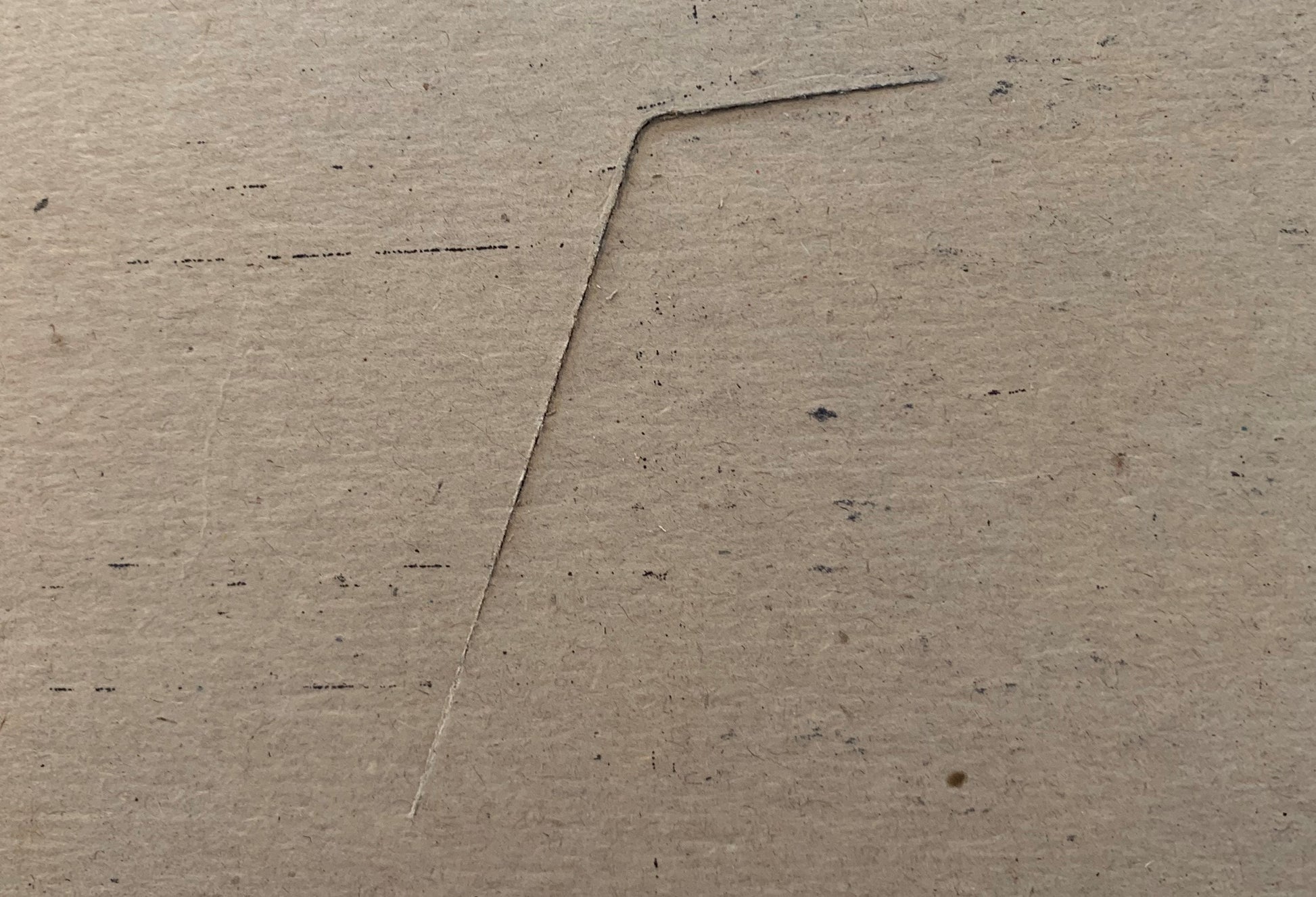 Close-up of a concrete or cement surface with a diagonal seam or joint line running across it, showing texture and small dark