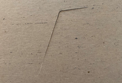 Close-up of a concrete or cement surface with a diagonal seam or joint line running across it, showing texture and small dark