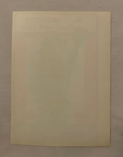 Cream-colored rectangular label or document on tan textile background, text barely visible due to age and lighting