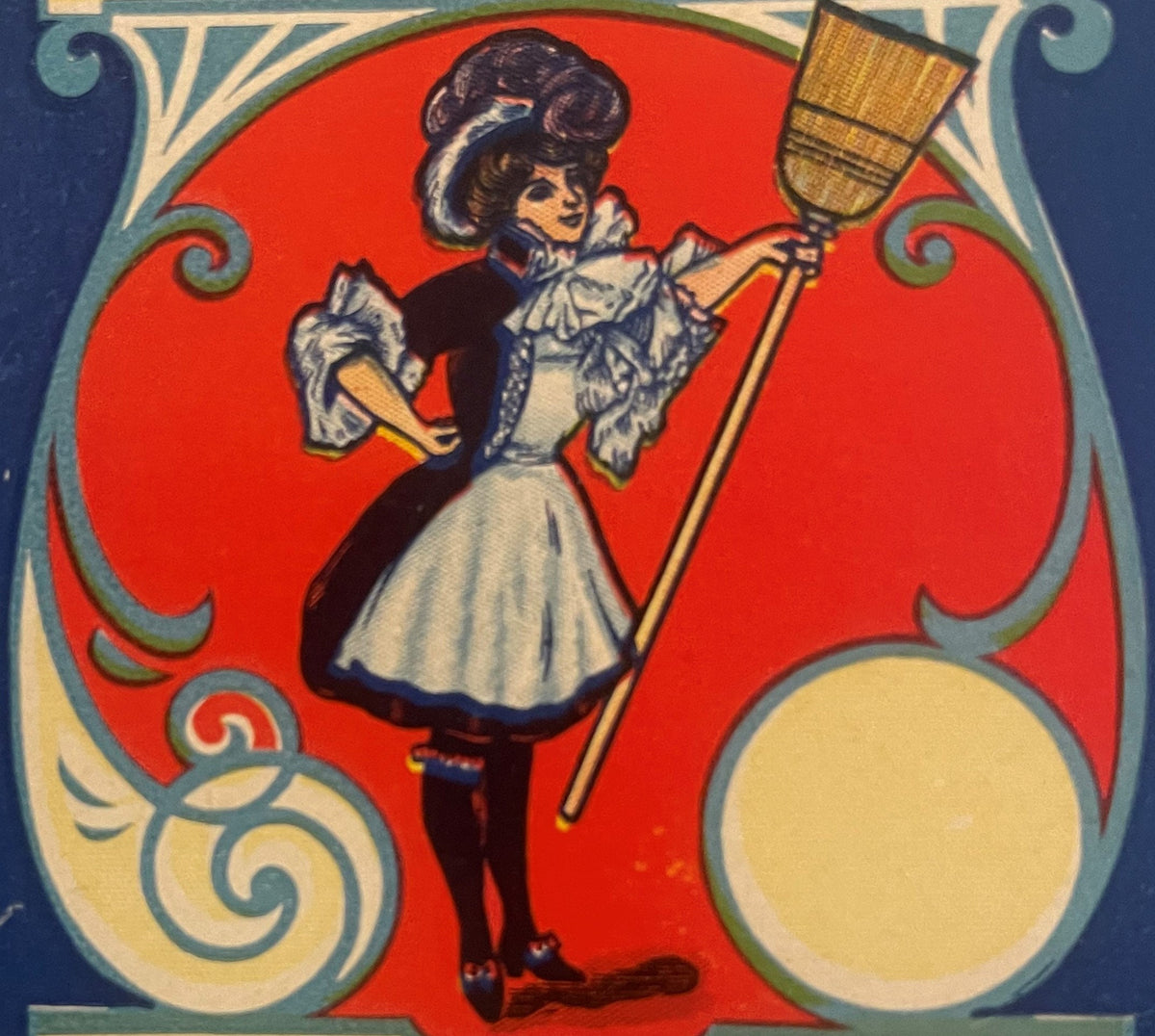 Vintage broom label featuring an Art Nouveau woman in white apron and dark dress holding a large broom against red background