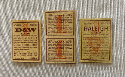Three vintage B&W and Raleigh tobacco coupons on tan cardstock with brown text, displayed on textured fabric background