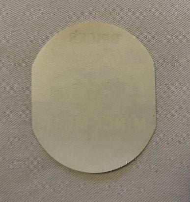 Cream-colored oval label with embossed text on textured background, photographed flat