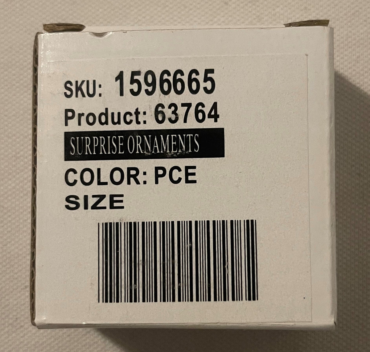 The white product box with its printed label: SURPRISE ORNAMENTS, colour PCE and a barcode