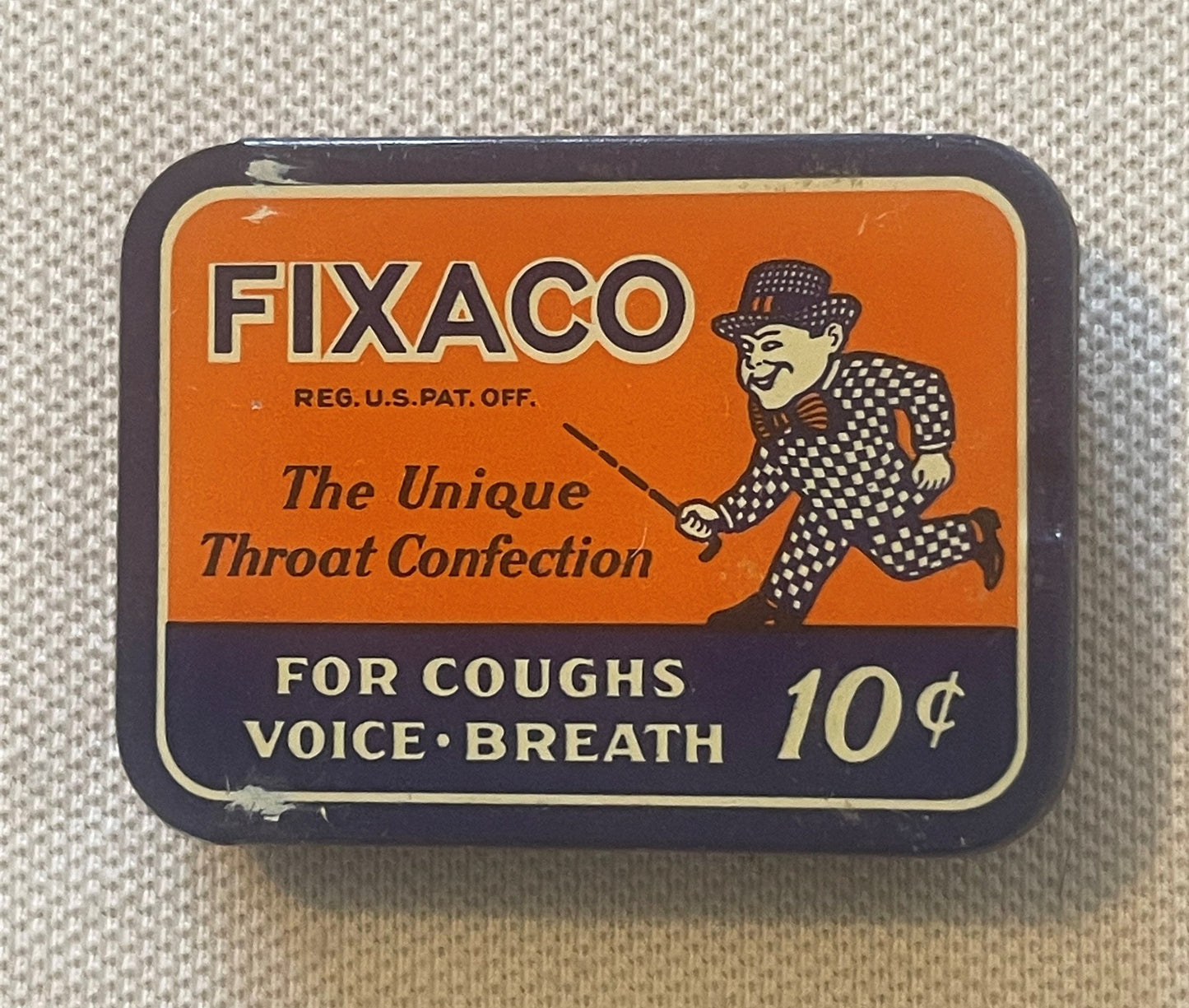 Front of the FIXACO throat confection tin: an orange label on a navy case, a man in a checked suit striding with a cane, and the lines The Unique Throat Confection / FOR COUGHS VOICE-BREATH / 10 cents.