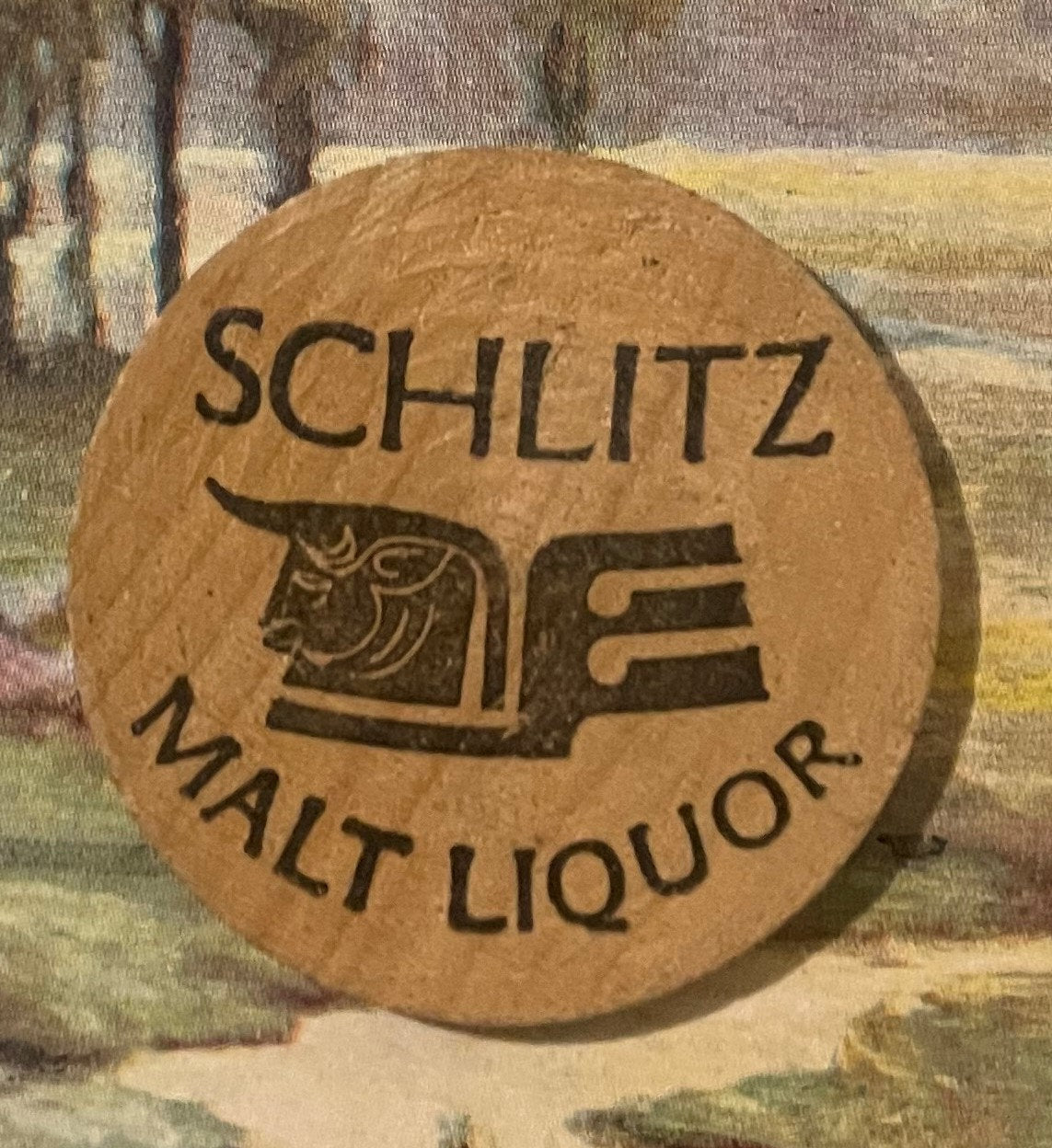 Wooden nickel with "SCHLITZ" text and Native American chief profile embossed, "MALT LIQUOR" below, tan circular disc