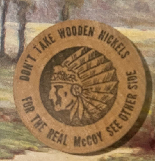 Wooden nickel with embossed Native American chief head profile and "Don't Take Wooden Nickels" text around rim, tan brown col