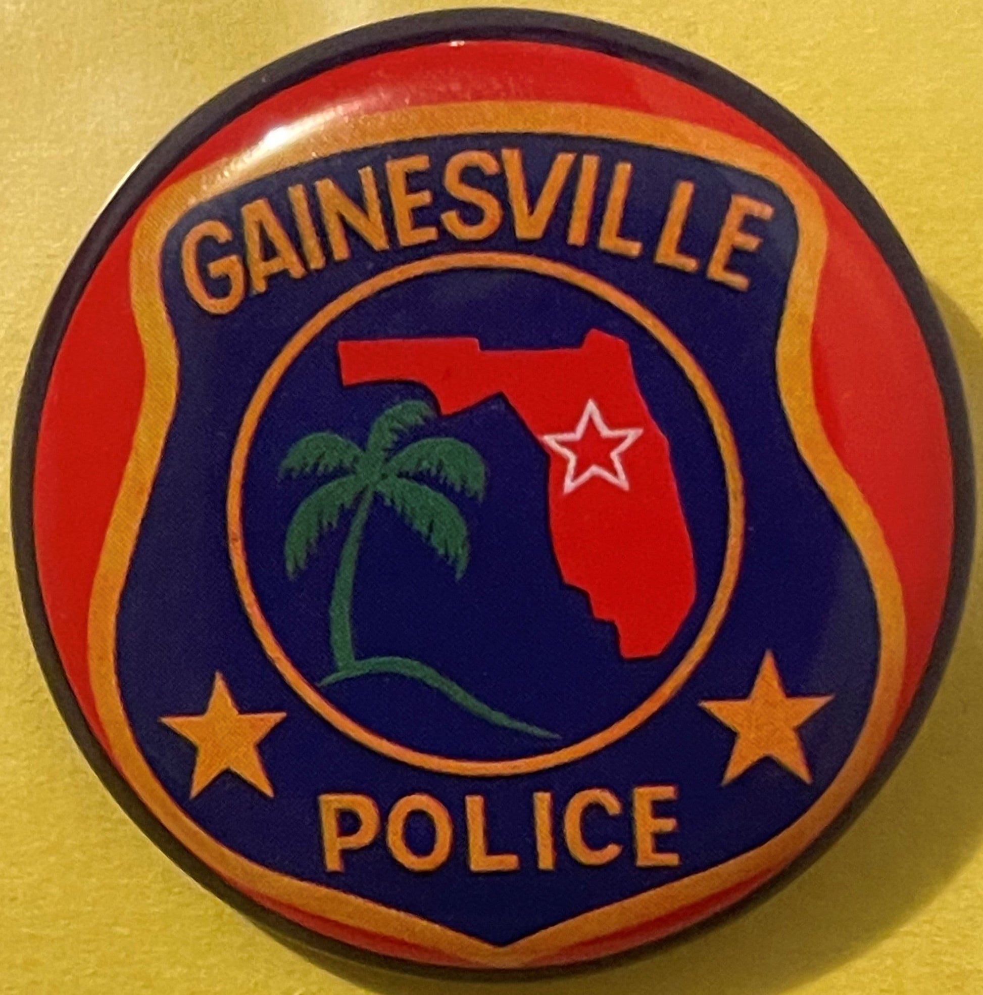Circular tin badge with dark blue center featuring red Florida state silhouette, green palm tree, and white star, surrounded 