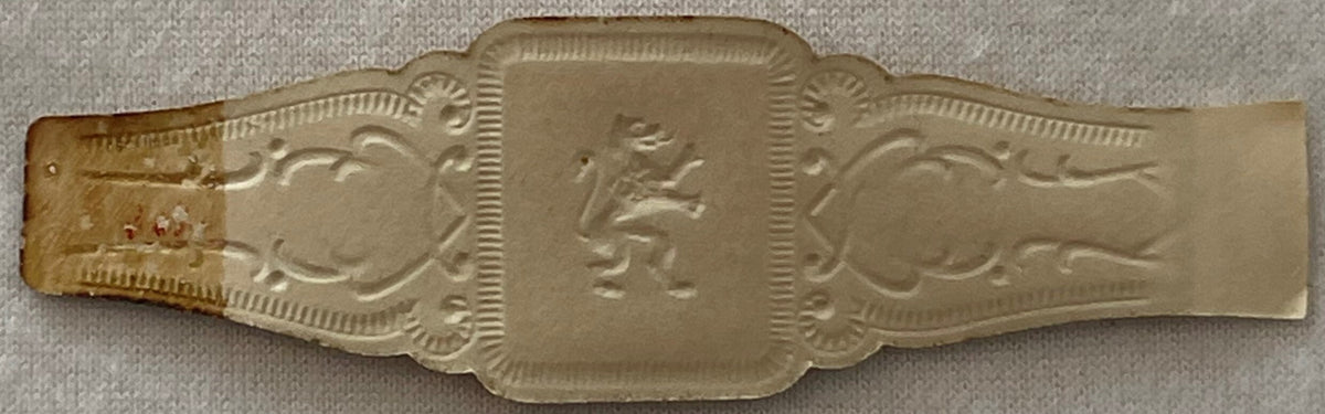 Ornate embossed cigar band with central profile portrait flanked by decorative scrollwork and shell motifs, tan metallic fini