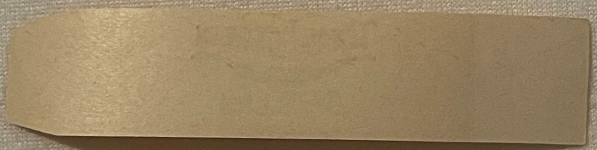 Tan cigar band with embossed border, photographed flat against textured background