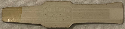Cream-colored rectangular cigar band with decorative notched edges, displayed on textured fabric background
