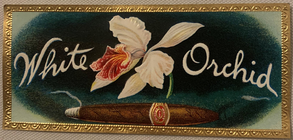 Antique cigar box label with white orchid flower and red center on dark green background, gold embossed border, brown cigar a
