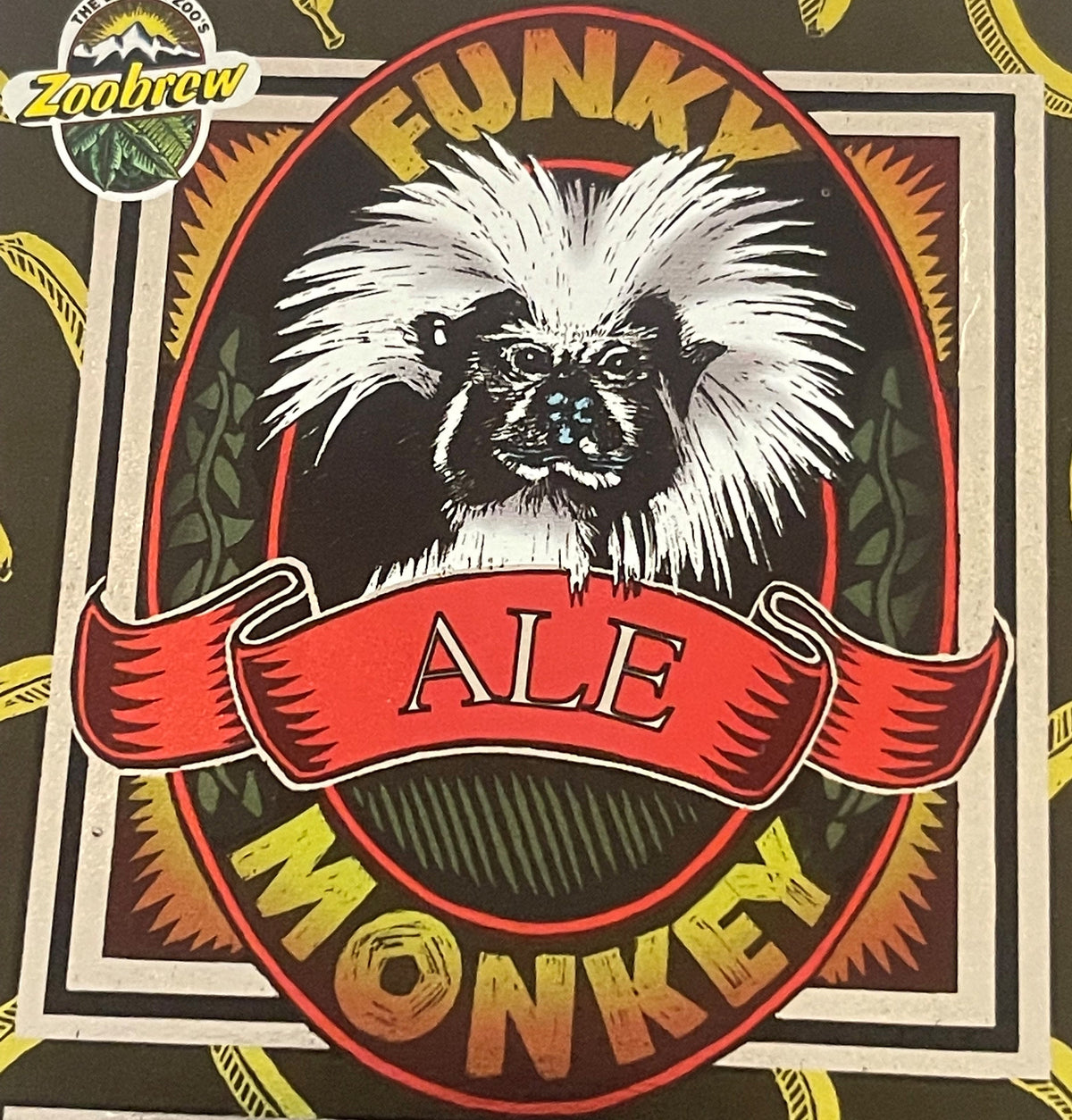 Close-up of the upper Funky Monkey Ale label: a cotton-top tamarin with a long white swept-back crest and dark face, in a black oval ringed red, FUNKY arched above in yellow, a red ALE banner below. Top left roundel: THE DENVER ZOO'S Zoobrew.