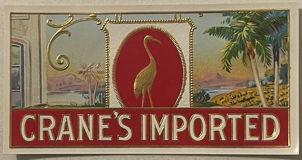 Vintage embossed cigar label featuring a gold crane on red background with tropical landscapes, ornate gold borders, and "CRA