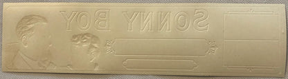 Embossed cellophane cigar box label with "Sonny Boy" text reversed, showing two male portrait profiles and decorative cartouc