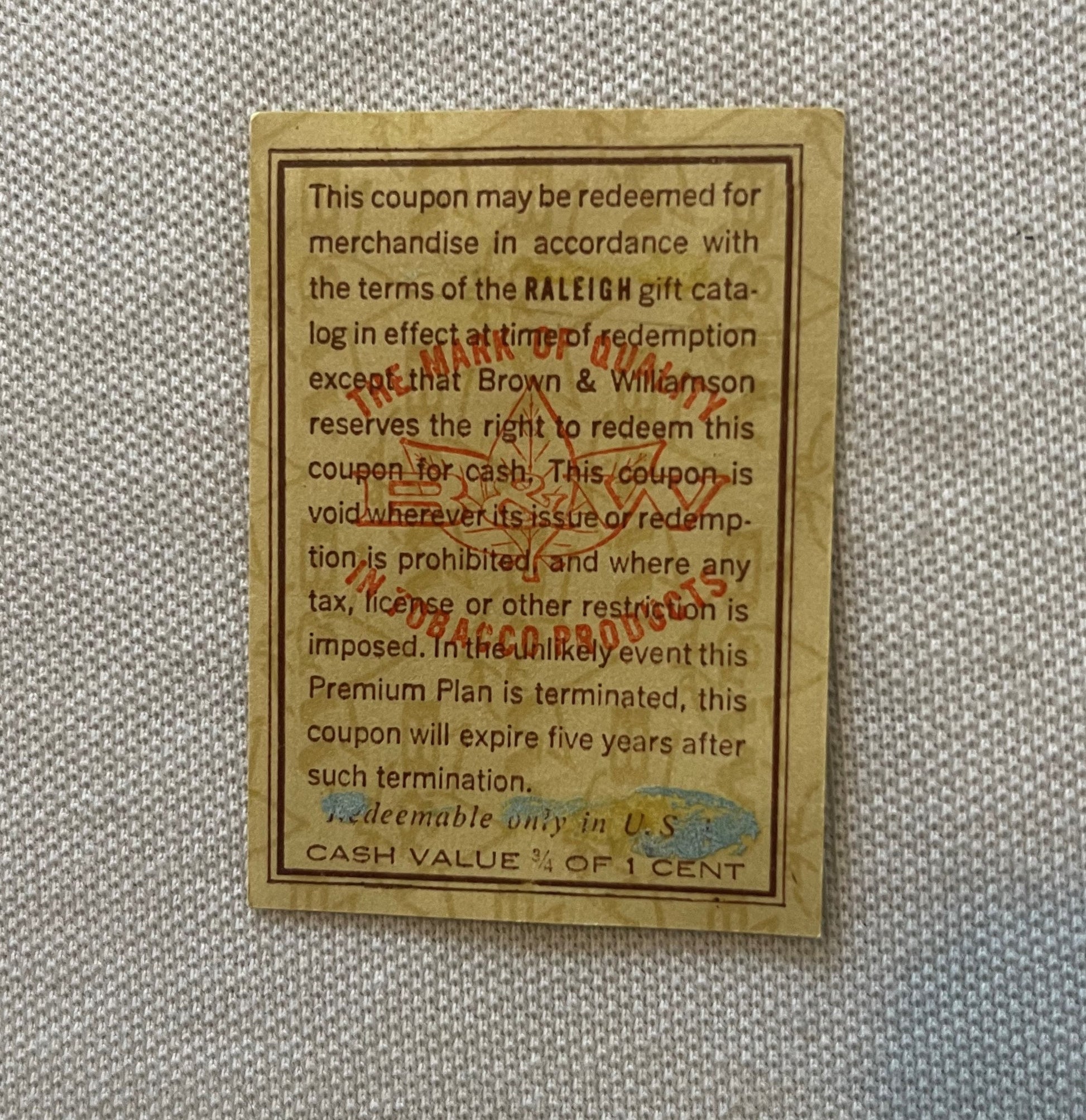 Vintage tan coupon from Raleigh tobacco with printed terms and conditions, showing cash value of 3/4 cent, displayed on gray 