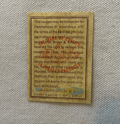 Vintage tan coupon from Raleigh tobacco with printed terms and conditions, showing cash value of 3/4 cent, displayed on gray 