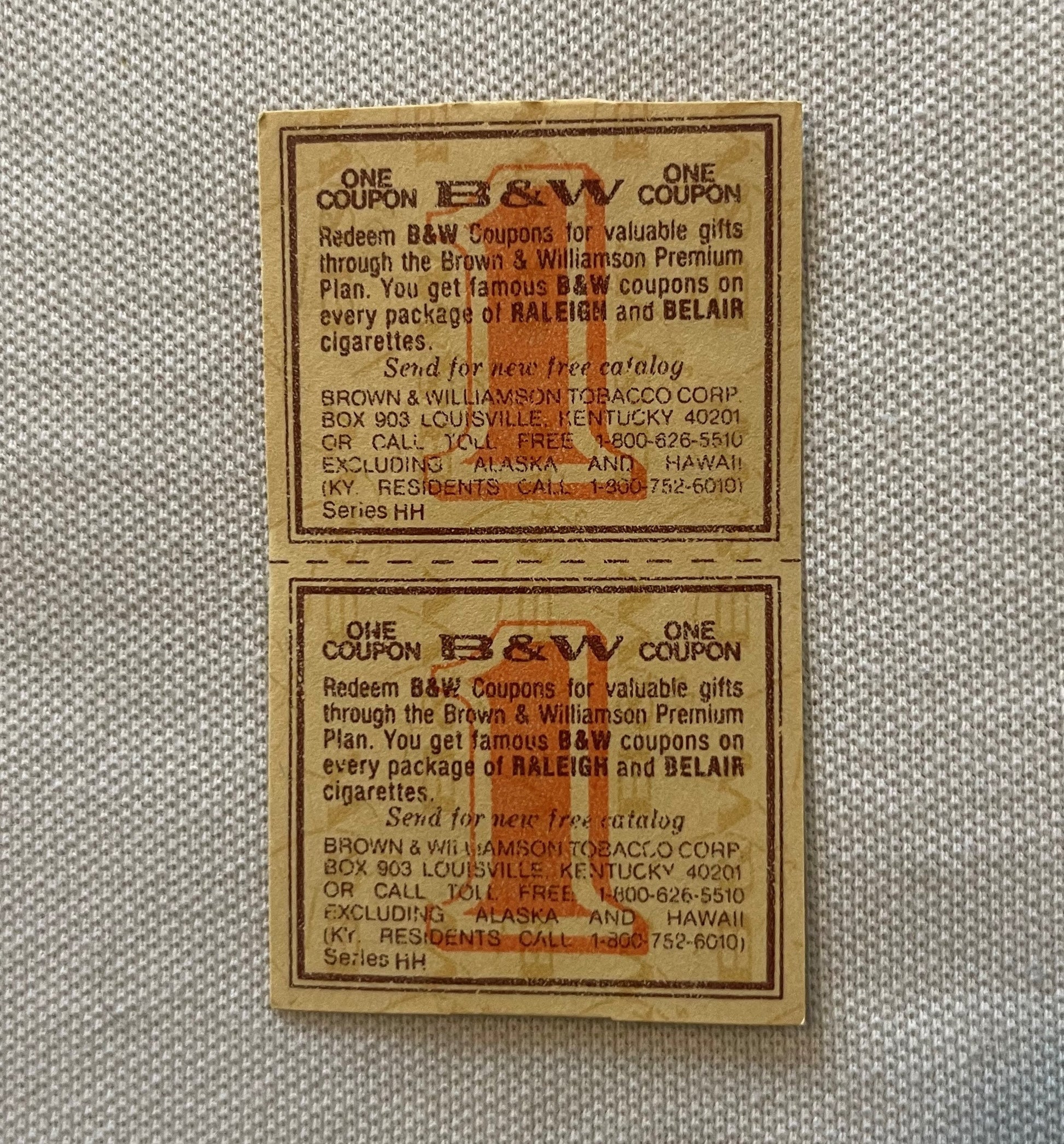 Two vintage B&W tobacco coupons from Brown & Williamson stacked vertically on beige fabric, printed text and orange logo visi
