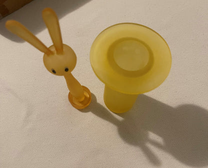 Amber yellow glass bunny toothpick holder photographed from above on white fabric, showing rabbit figurine with long ears and