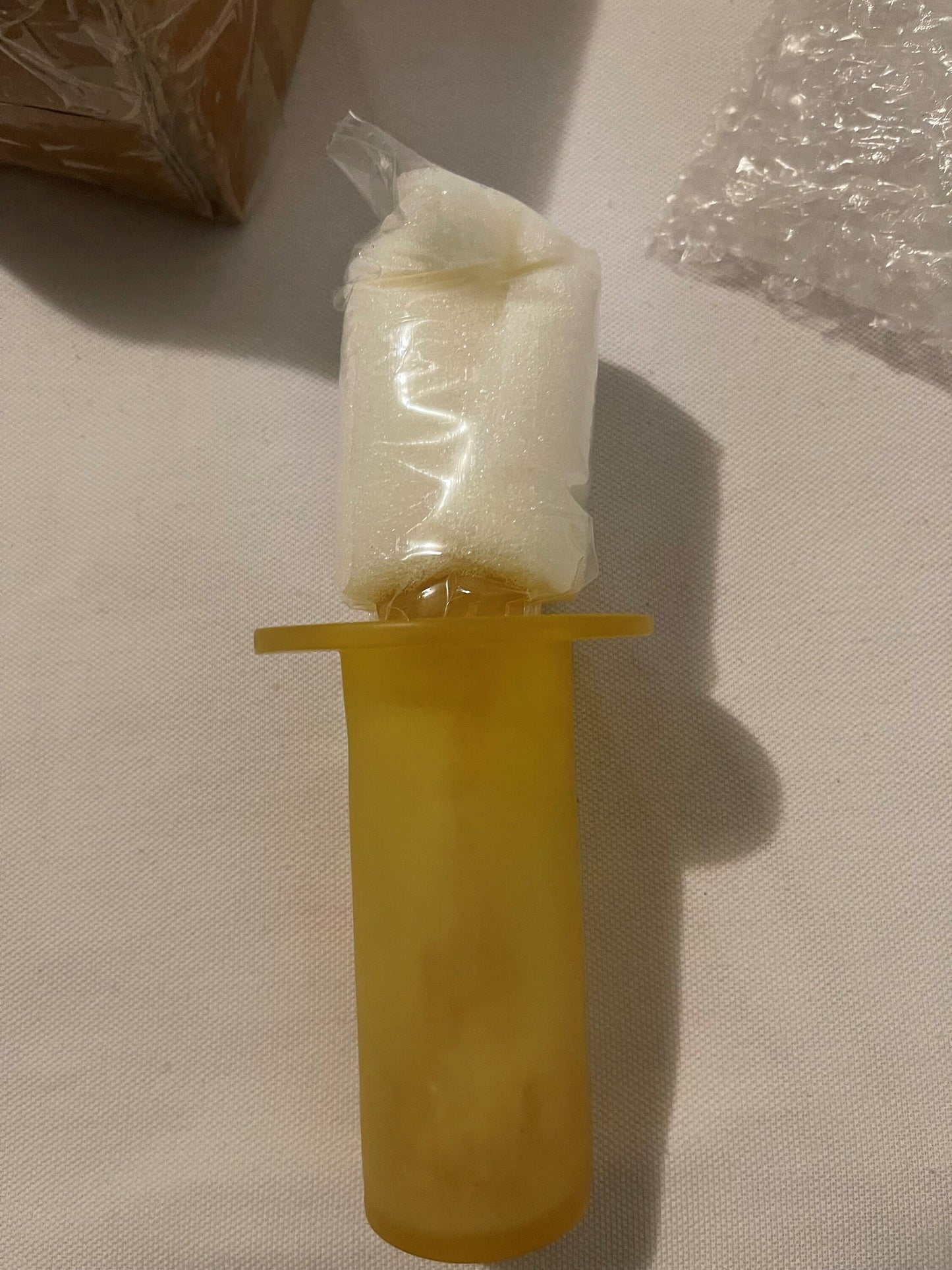 Amber yellow plastic rabbit toothpick holder with clear plastic bag on top, displayed against white textured background with 