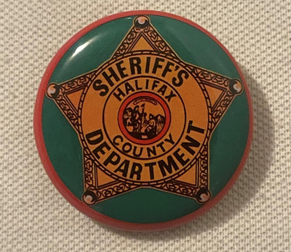Vintage sheriff's badge pin with gold star on green and red circular tin background