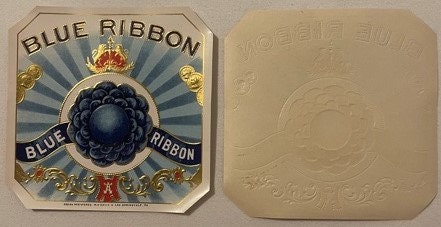 Front and back of ornate blue cigar box label with gold embossed text and central black medallion design on cream colored pap