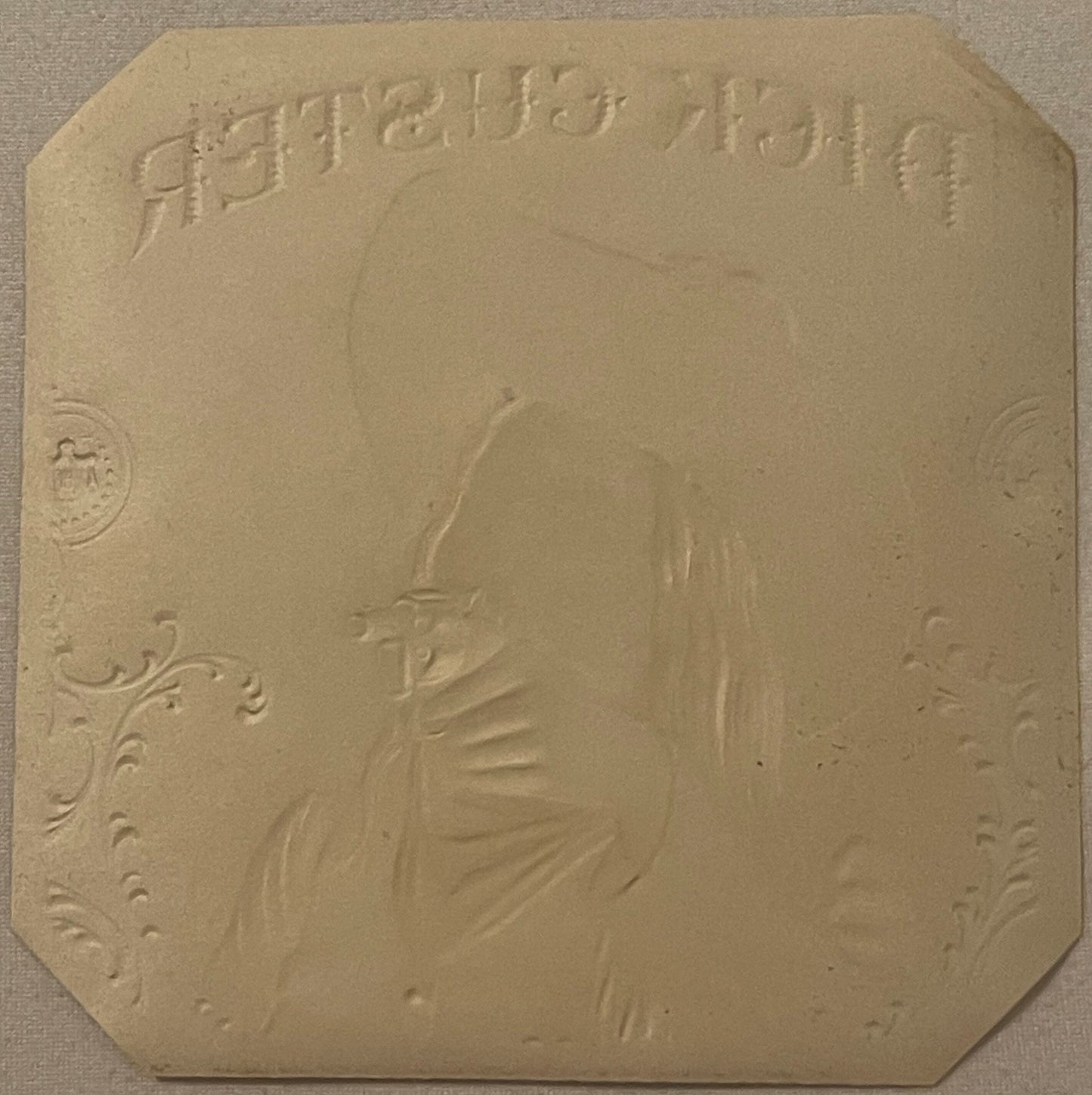 Cream-colored embossed label with cowboy profile in center, decorative corner flourishes, and text reading "Dick Custer" at t