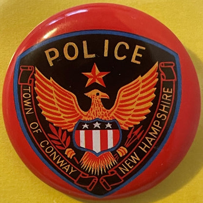 Vintage tin litho police badge with red rim, black and blue shield, gold eagle, star, and shield emblem on yellow background.
