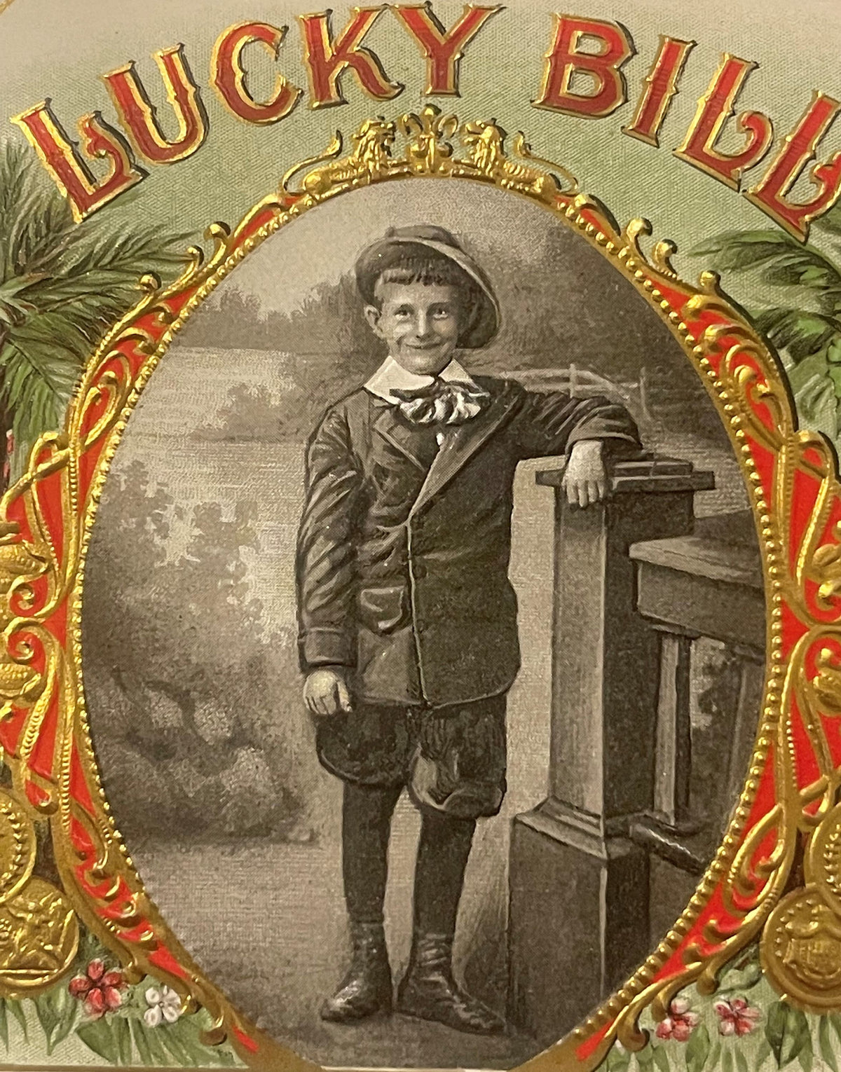 Antique Lucky Bill cigar box label with ornate gold and red frame, young boy in period clothing leaning against wooden furnit