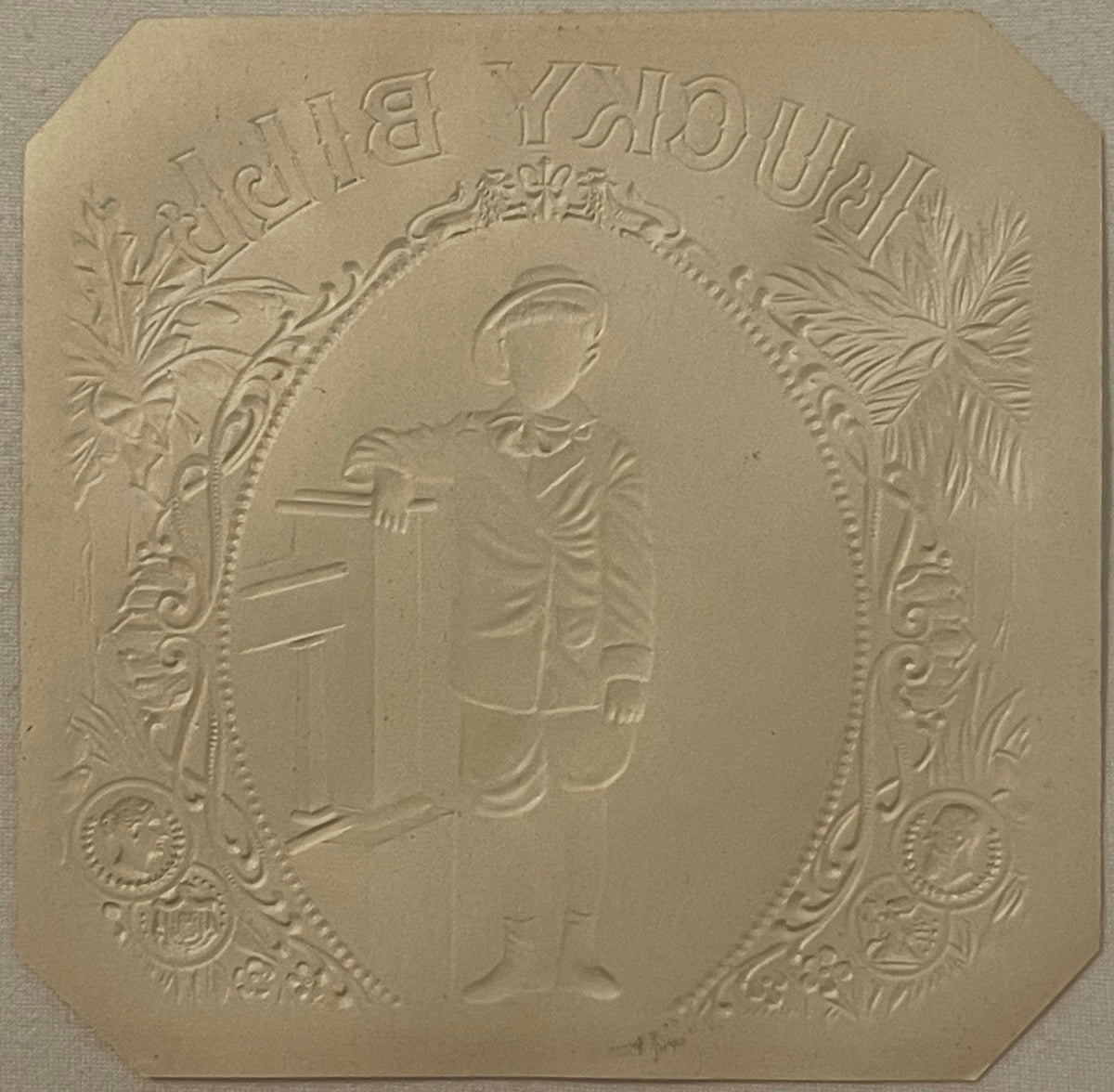 Embossed cream-colored cigar box label showing a classical male profile in oval frame with ornate botanical borders and text 