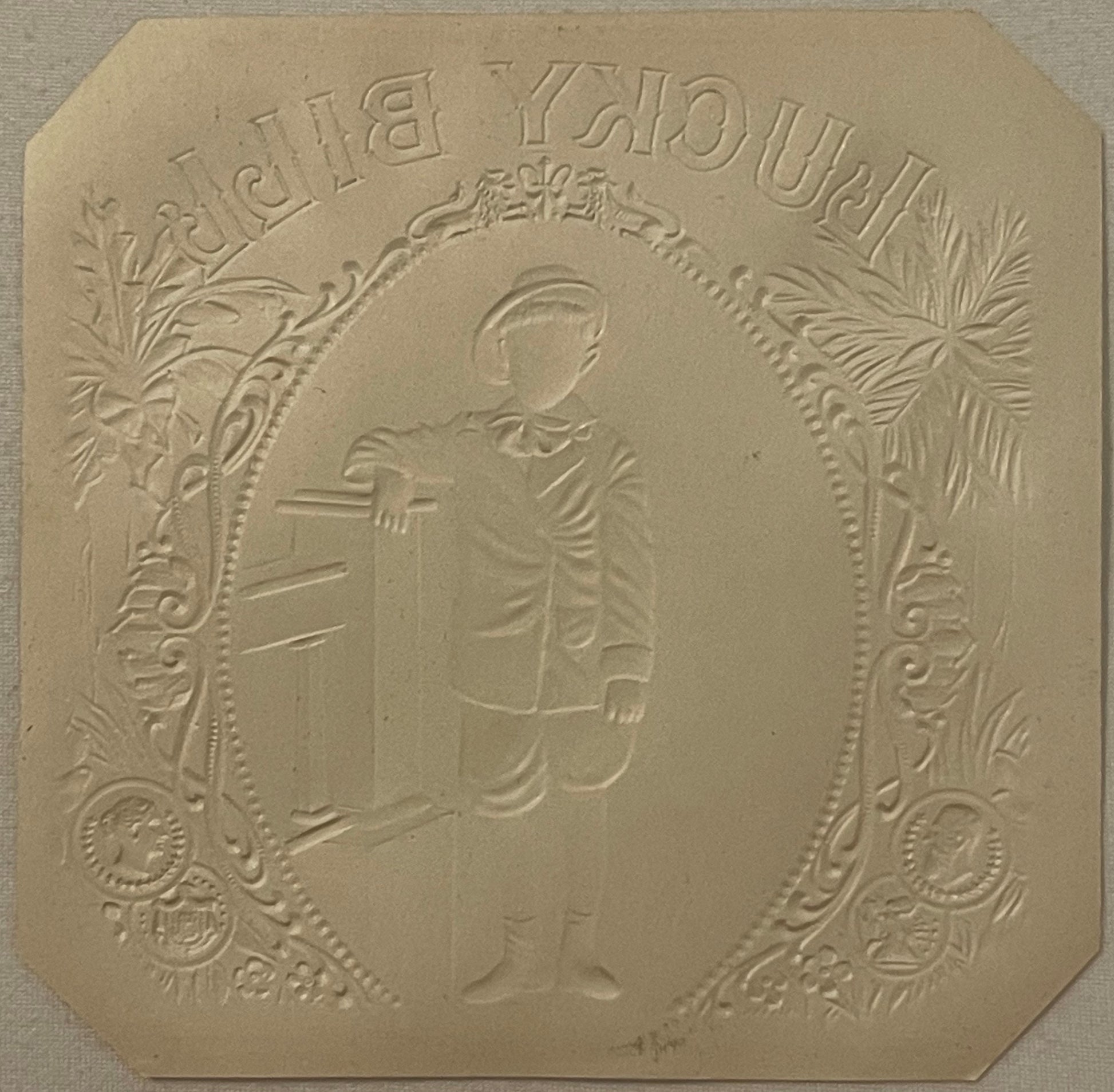 Embossed cream-colored cigar box label showing a classical male profile in oval frame with ornate botanical borders and text 