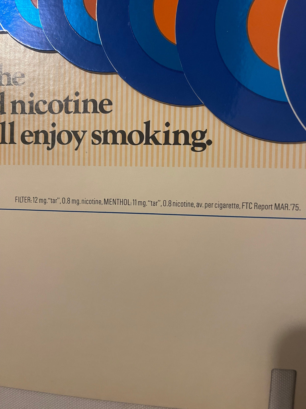 Close-up of vintage cigarette pack display showing blue and orange curved design elements with partial