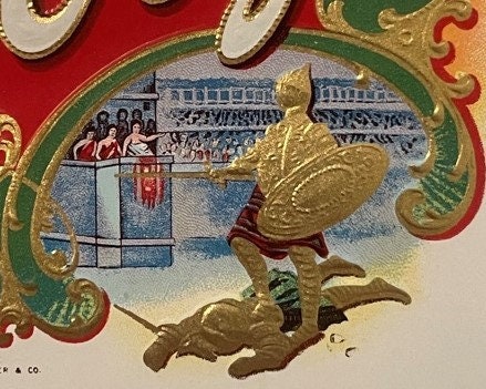 Embossed cigar label with gold gladiator figure, Roman amphitheater scene, red and green decorative borders, ornate scrollwor