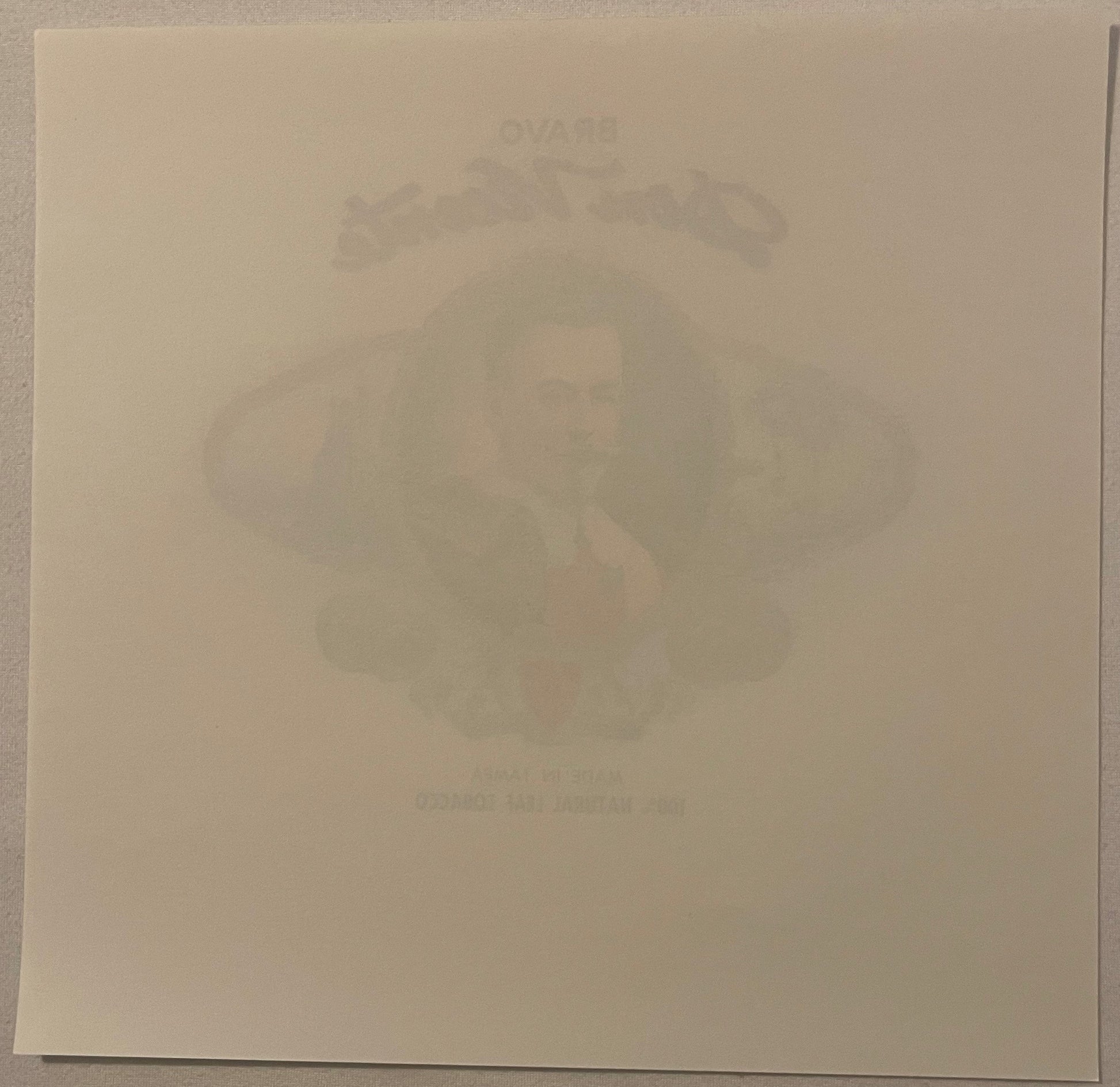 Faded embossed cigar box label showing a man's portrait, tan paper background, barely legible text at top and bottom