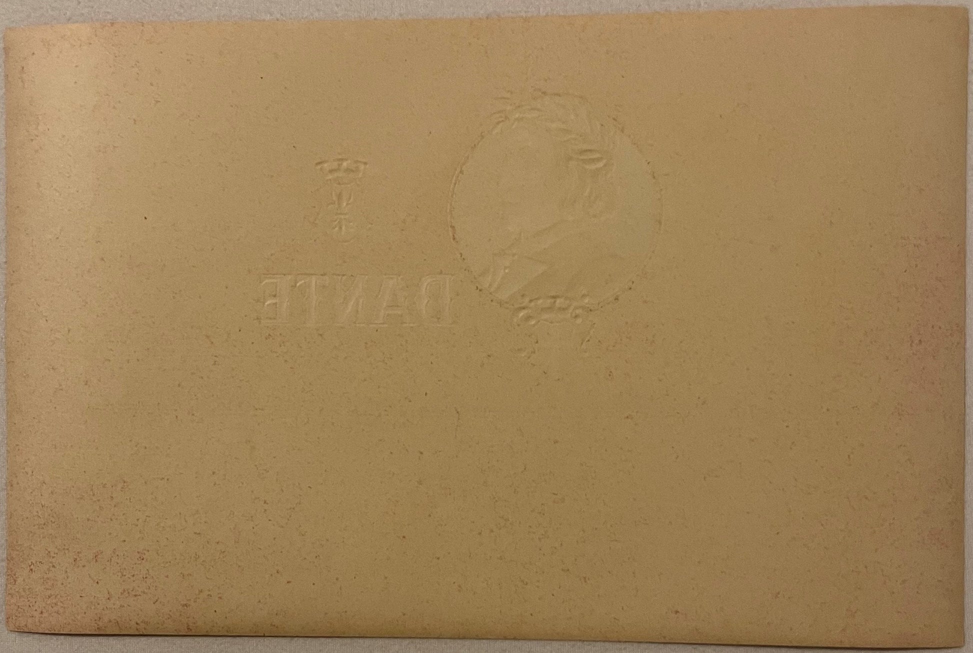 Tan cardstock with embossed portrait in oval frame and text reading "DANTE" and "SULZBERGER-OPPENHEI", photographed flat on t