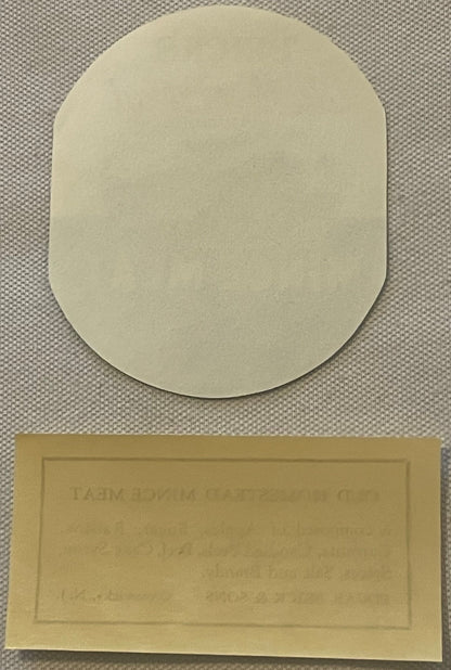Two cream-colored vintage labels on textured fabric background; top label is rounded rectangle, bottom label is rectangular w