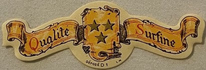 Vintage die-cut paper neck label with gold and cream coloring, reading "Qualite" and "Surfine" on ribbons with central shield