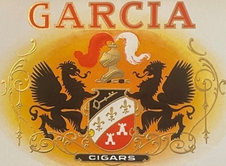 Ornate vintage Garcia cigar label with gold embossing, two black dragons flanking a coat of arms, and yellow sunburst backgro
