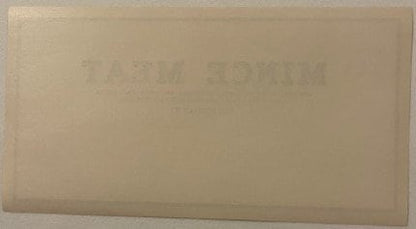 Back of the unprinted mince meat stock label: blank cream paper with no printing at all, showing only the front's MINCE MEAT lettering ghosting through the sheet in mirror image