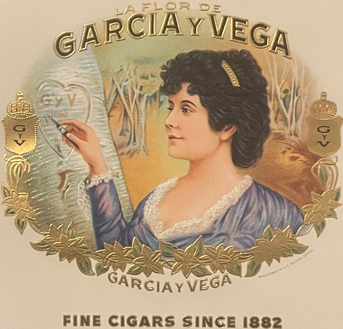 Vintage cigar box label with embossed gold foil showing a woman in profile wearing a blue dress, surrounded by decorative gol