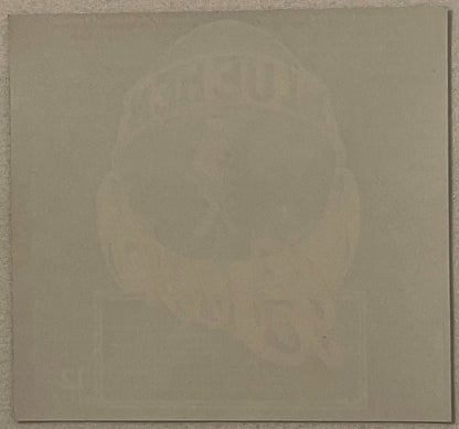 Blank cream-colored paper or backing against gray textured surface, no visible beer label or text