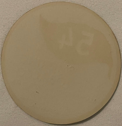 Blank cream-colored circular tobacco label on textured beige fabric background, showing wear marks and slight discoloration