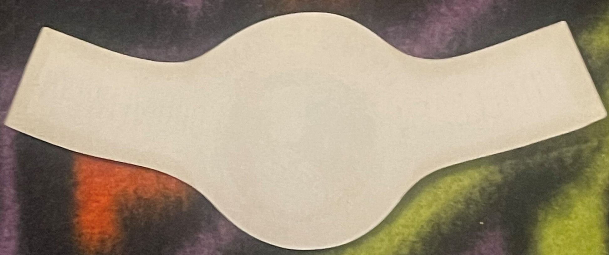 Blank cream-colored curved wine bottle neck label against colorful textured background with orange and green tones