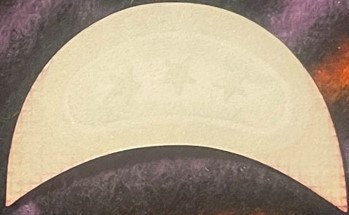 Cream-colored embossed crescent-shaped wine label with three stars design on dark textured background