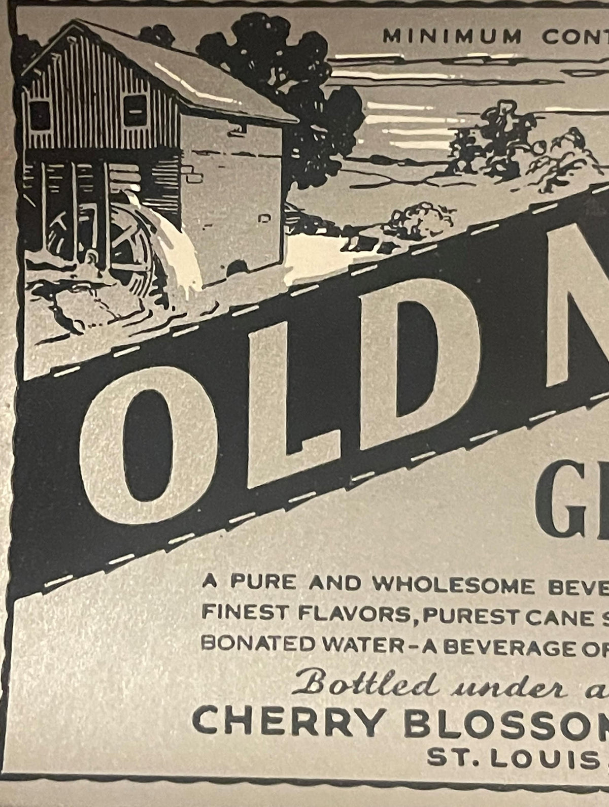 Vintage ginger ale label featuring large "OLD M" text, rural mill building illustration, and "Cherry Blossom St. Louis" brand